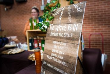 A menu of potions and spells for sale by a witch at festival of freaks.