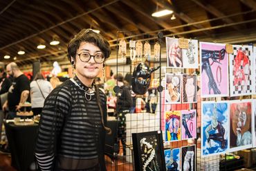 A vendor standing next to their artwork for sale.