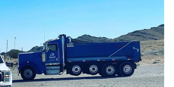 Blue dump truck on a gravel lot.