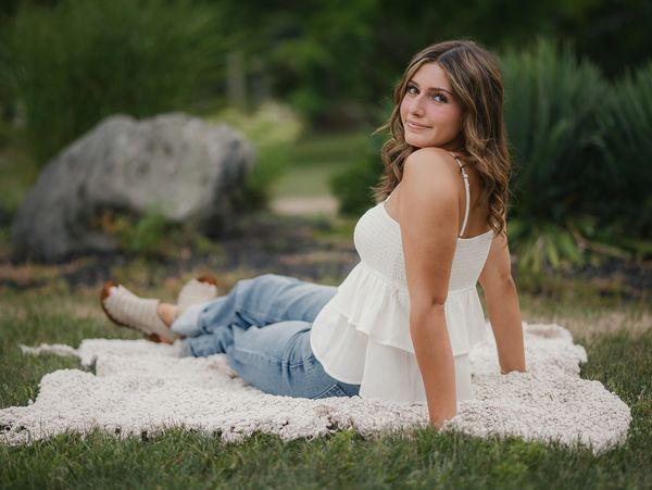 Young woman relaxing on a blanket outdoors in casual attire.