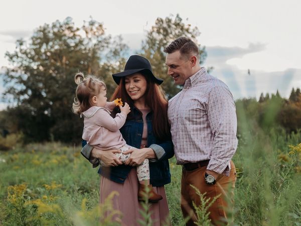 Family sharing a joyful moment in a green field with wildflowers. Family Portrait Mini Sessions