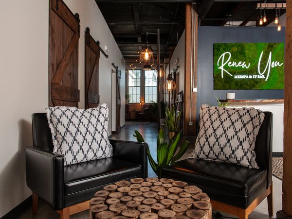 Cozy seating area with leather chairs and wooden table in a stylish medspa lobby.