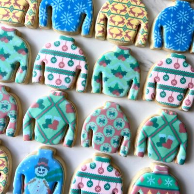 Festive sweater-shaped cookies with colorful holiday designs.