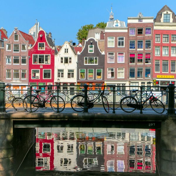 Colorful canal houses and bicycles in Amsterdam reflected in water.