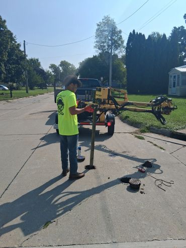 Worker operating a drilling machine on a residential street.