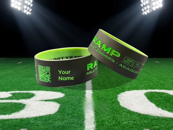 Two black silicone wristbands on a football field with QR code and Your Name on them