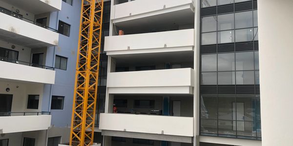Modern apartment building under construction with yellow crane.
