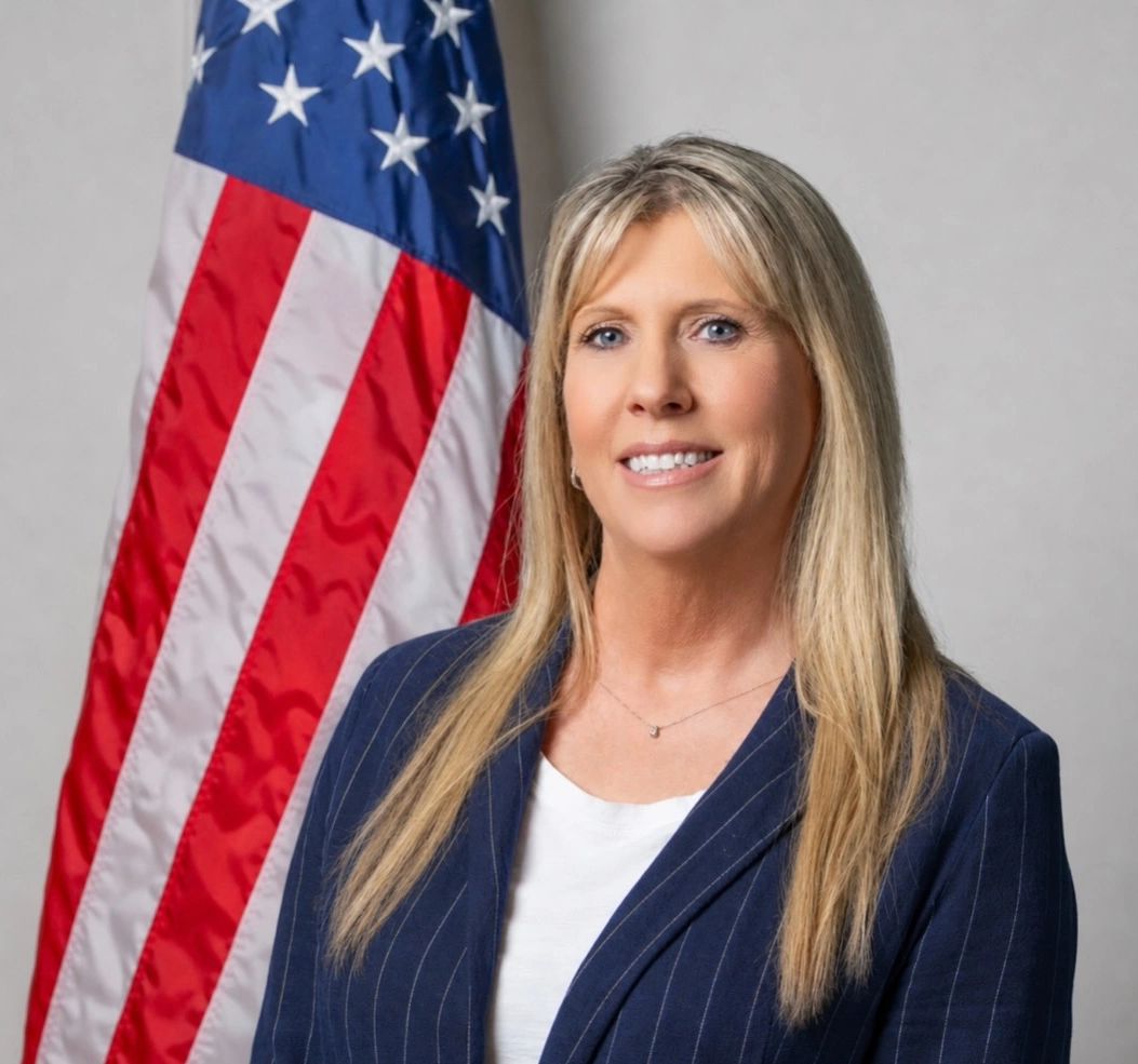 Professional woman posing with an American flag backdrop.