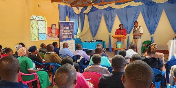 Church leaders conference with speakers at podium.