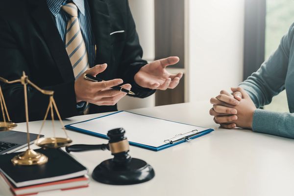 A lawyer in a suit discusses a case with a client, surrounded by legal documents