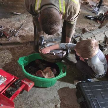 Man and boy working together on a tire in a garage.