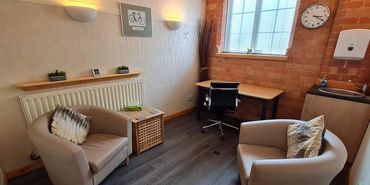 The Raleigh Room, Humber Therapy Centre. Two tub chairs, a desk, a sink, windows and soft lighting.