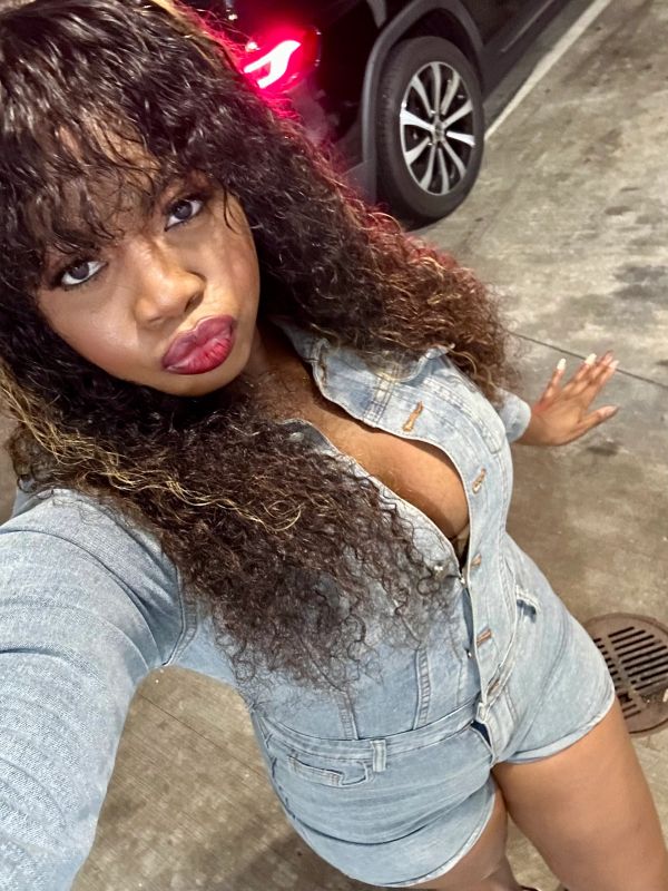 Woman in denim outfit taking a selfie outdoors at night.