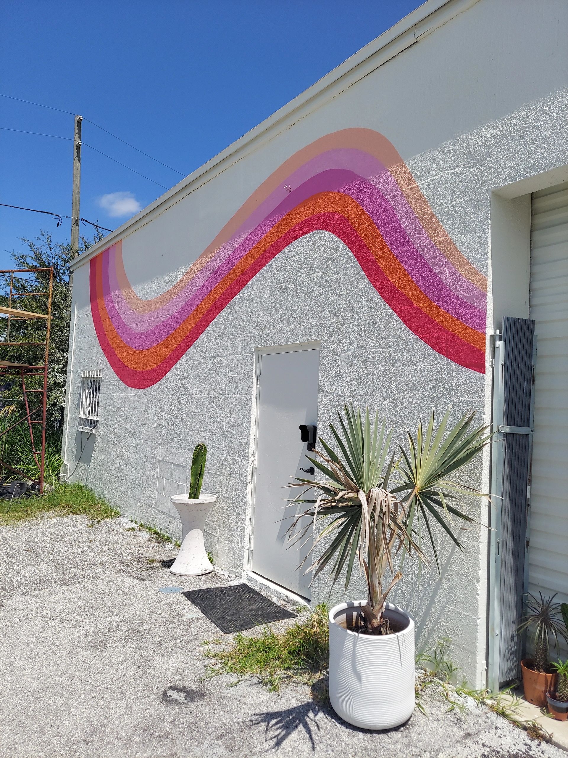 Bold Mural painted on white wall featuring smooth wavy stripe moving across wall in reds and pinks.