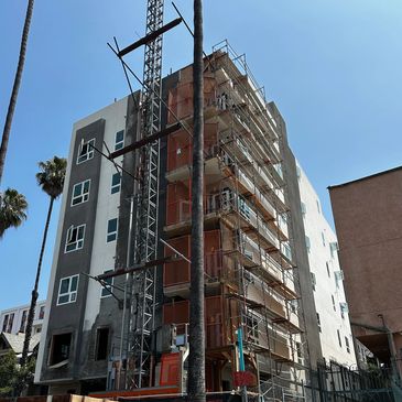 Multi-story building under construction with scaffolding and a clear sky.