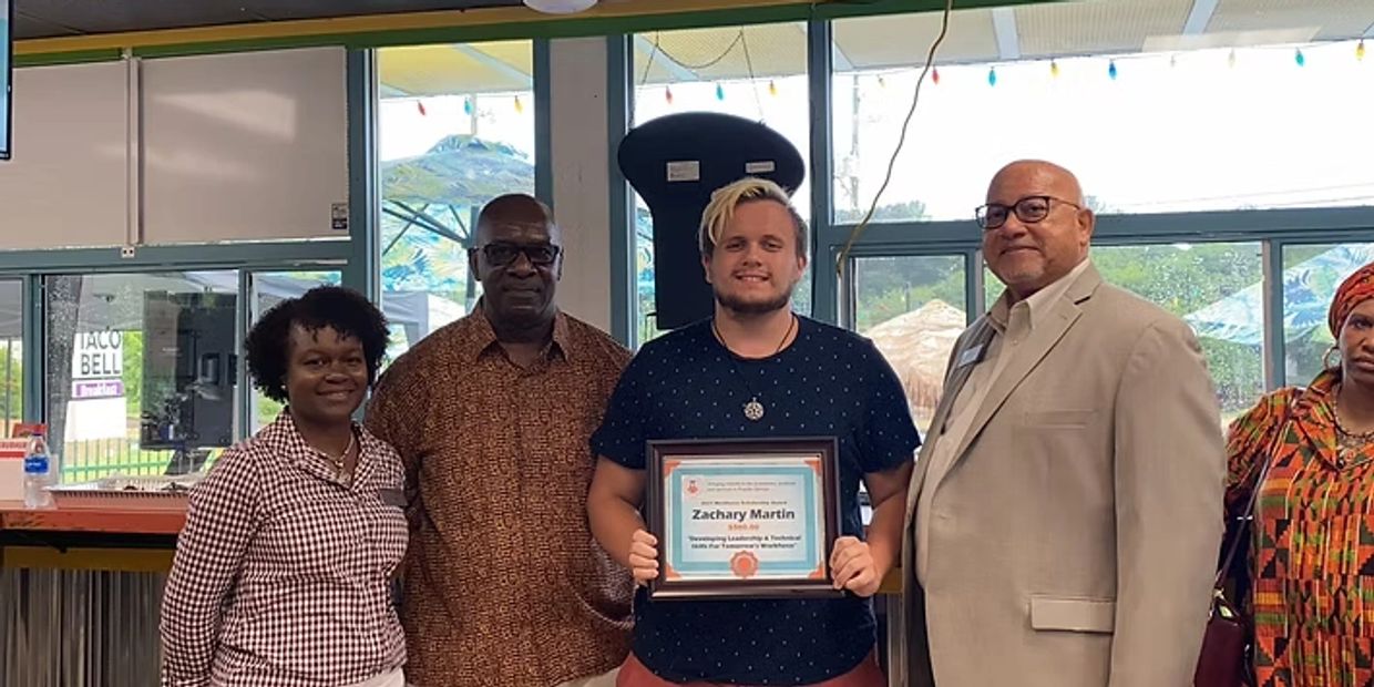 Award recipient standing with certificate and Five colleagues