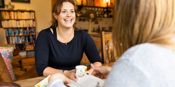 Two women enjoying conversation over coffee indoors.