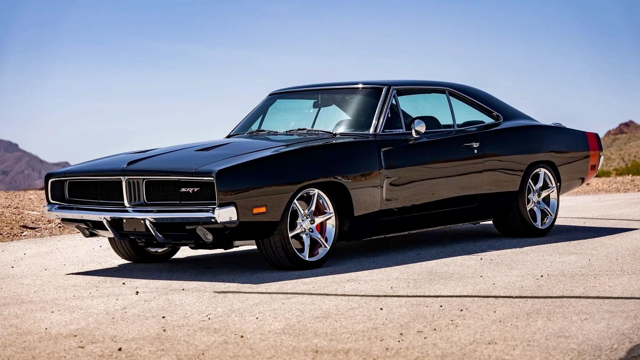Classic black Dodge Charger SRT parked on a sunny road in a desert setting.