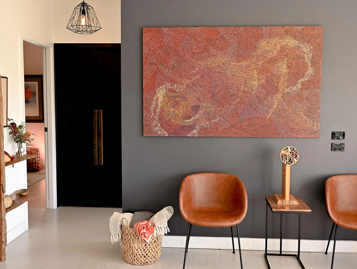 Sitting area with black wall and bright Aboriginal artwork