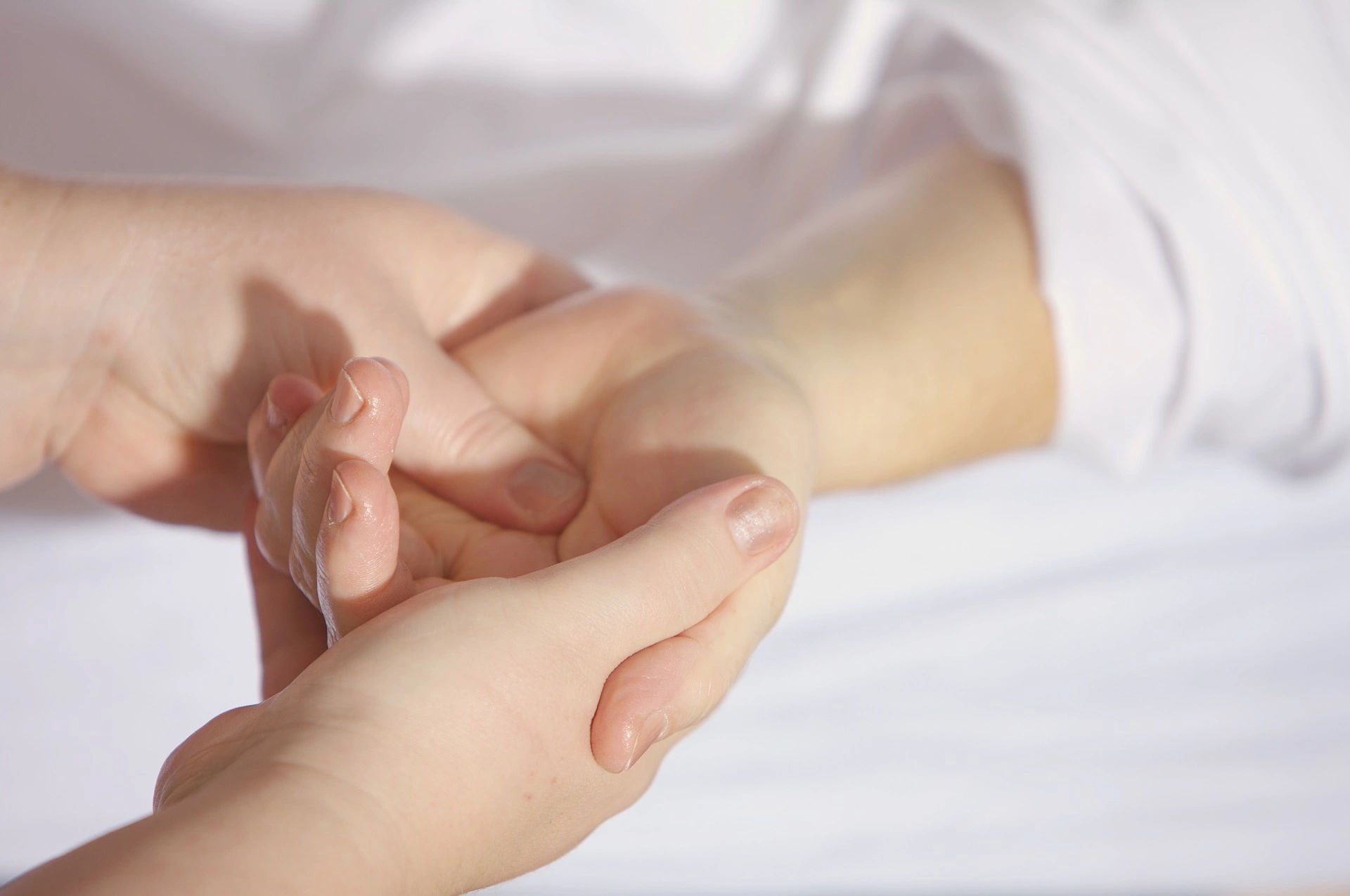 Massage Therapist massaging a clients hand with thumbs