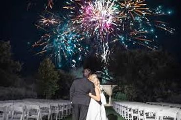 Another couple celebrating with a beautiful fireworks show in the background.