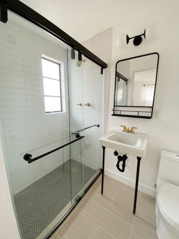 Modern bathroom with glass shower, black accents, and minimalist design.