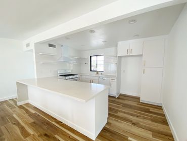 Modern white kitchen with wooden floors and a large island counter.