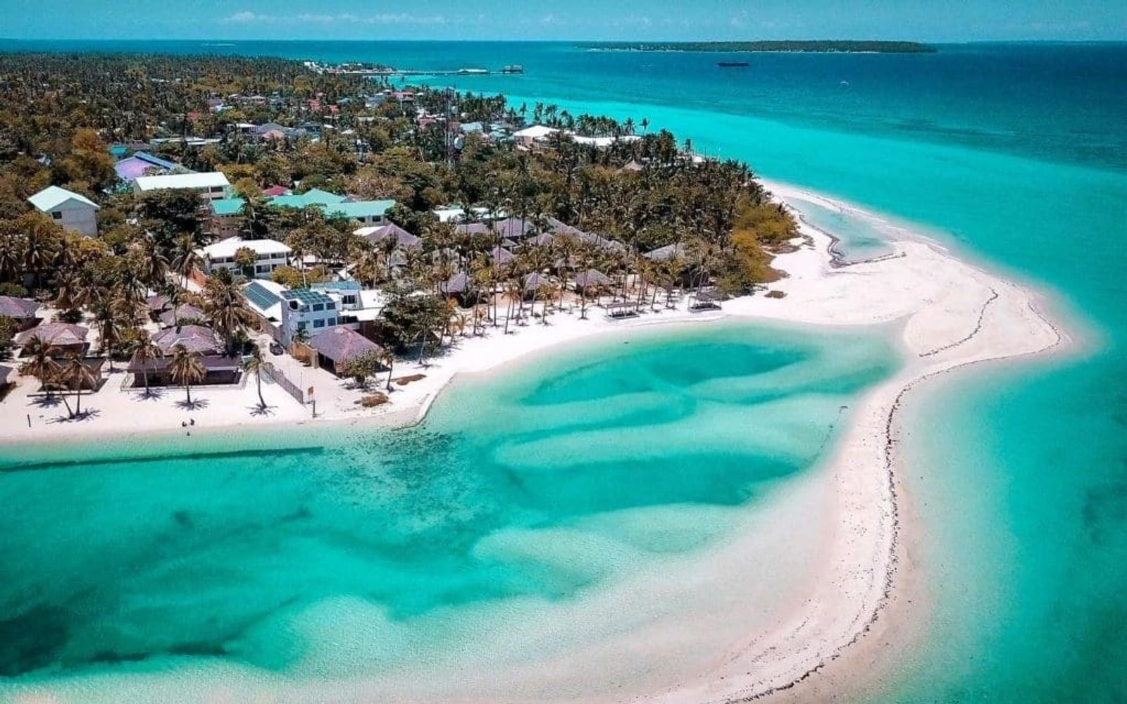 Aerial view of a tropical island with clear turquoise water and white sandy beaches.
