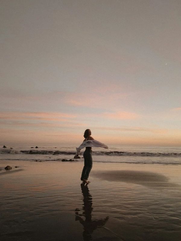 Person spinning on a beach at sunset.