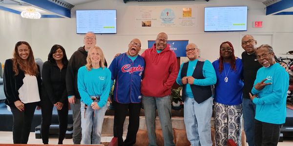 A diverse group of adults smiling and posing indoors in a cheerful setting.