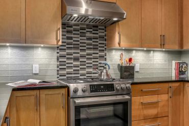 Modern kitchen with stainless steel stove and stylish backsplash.