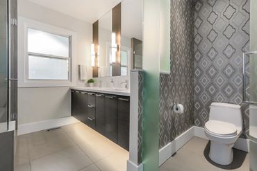 Modern bathroom with double vanity and patterned accent wall.