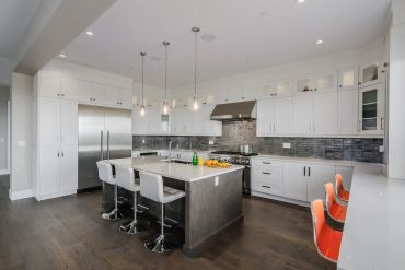 Modern kitchen with white cabinets, stainless steel appliances, and a large island with seating.