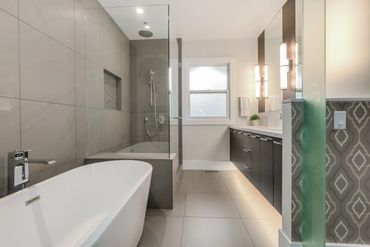 Modern bathroom with a bathtub, glass shower, and double sink vanity under bright lighting.