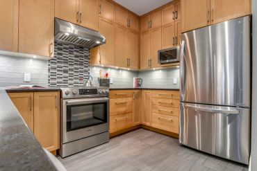 Modern kitchen with stainless steel appliances and wooden cabinets.