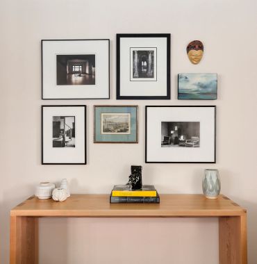 A wooden table with decor and framed art on the wall above it.