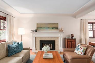 Cozy living room with a fireplace, neutral tones, and colorful cushions.