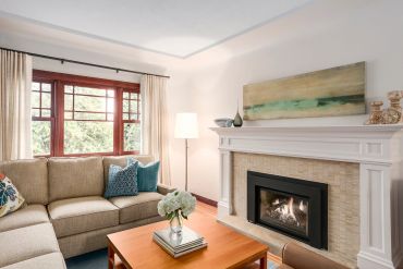 Cozy living room with beige sofa, fireplace, and wooden coffee table.