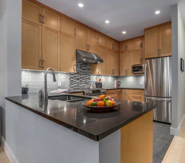 Modern kitchen with wooden cabinets and a black countertop island.