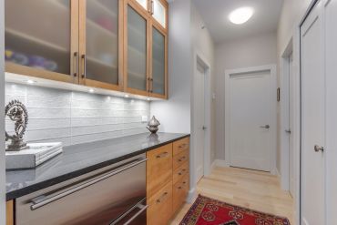Modern hallway with wooden cabinets, black countertop, and a red rug.