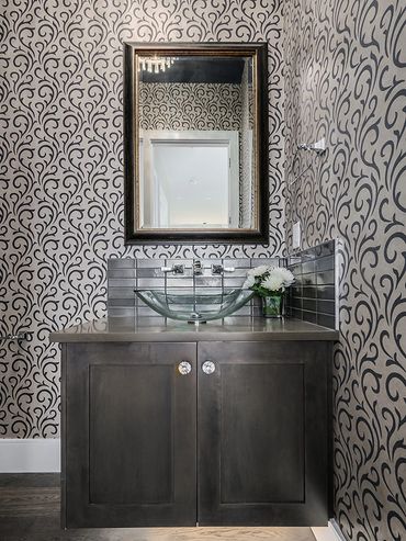 Elegant bathroom vanity with patterned wallpaper and glass vessel sink.