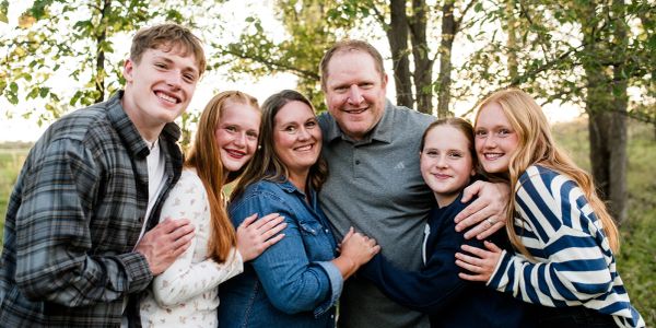 Happy family outdoors hugging and smiling.