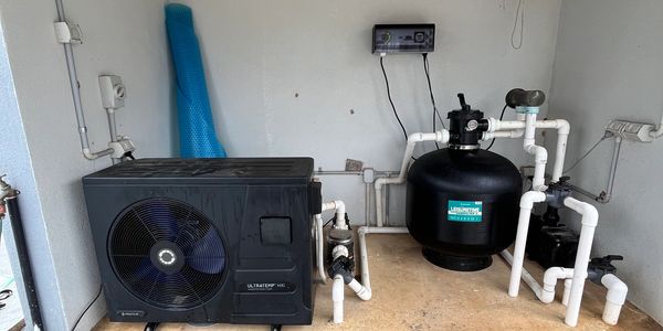 Indoor pool pump and filtration system setup with connected pipes and control panel.