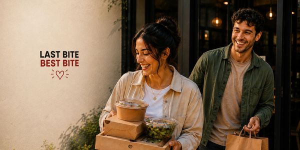 Two friends happily carrying takeout food packages outside a restaurant.