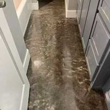 A narrow kitchen hallway with dark marbled flooring and gray cabinets.