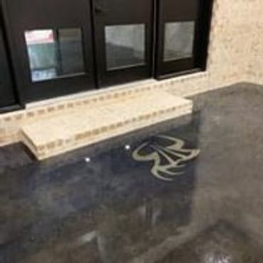 Polished floor with a decorative emblem and small steps near glass windows.