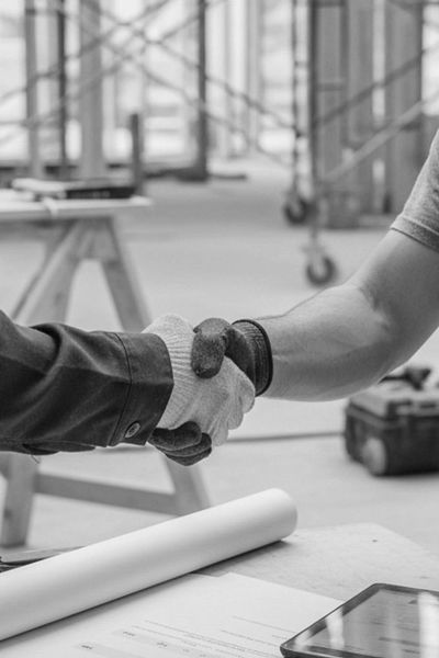 Two people shaking hands, wearing work gloves.