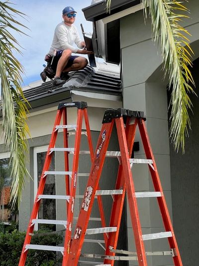 Man working on a roof with two ladders.