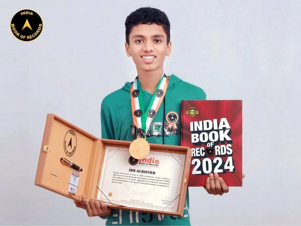 Young boy holding India Book of Records 2024 with a medal and certificate.
