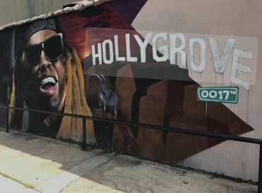 Street mural featuring a person with sunglasses and the word HOLLYGROVE.